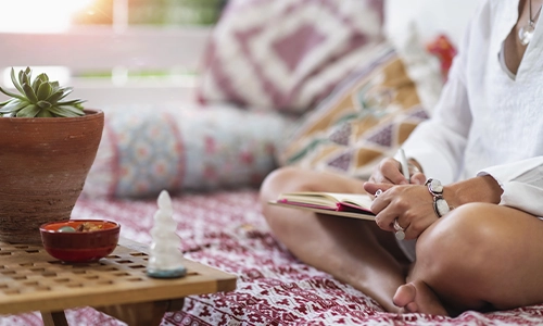 Woman seated taking notes in a notebook for counseling services.